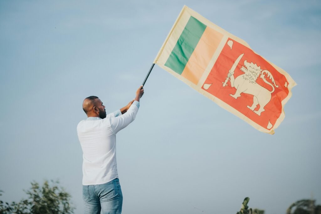 pexels photo 15317338 15317338 A man proudly waves the Sri Lankan flag outdoors under a clear blue sky, symbolizing national pride.